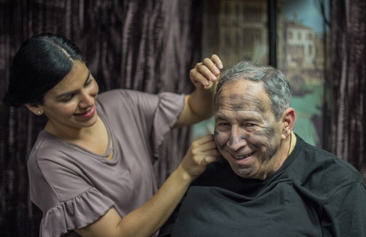 an actor is sitting down while his make up is being applied