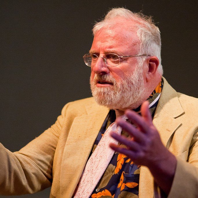 a person with glasses and white hair and beard, raising his arms