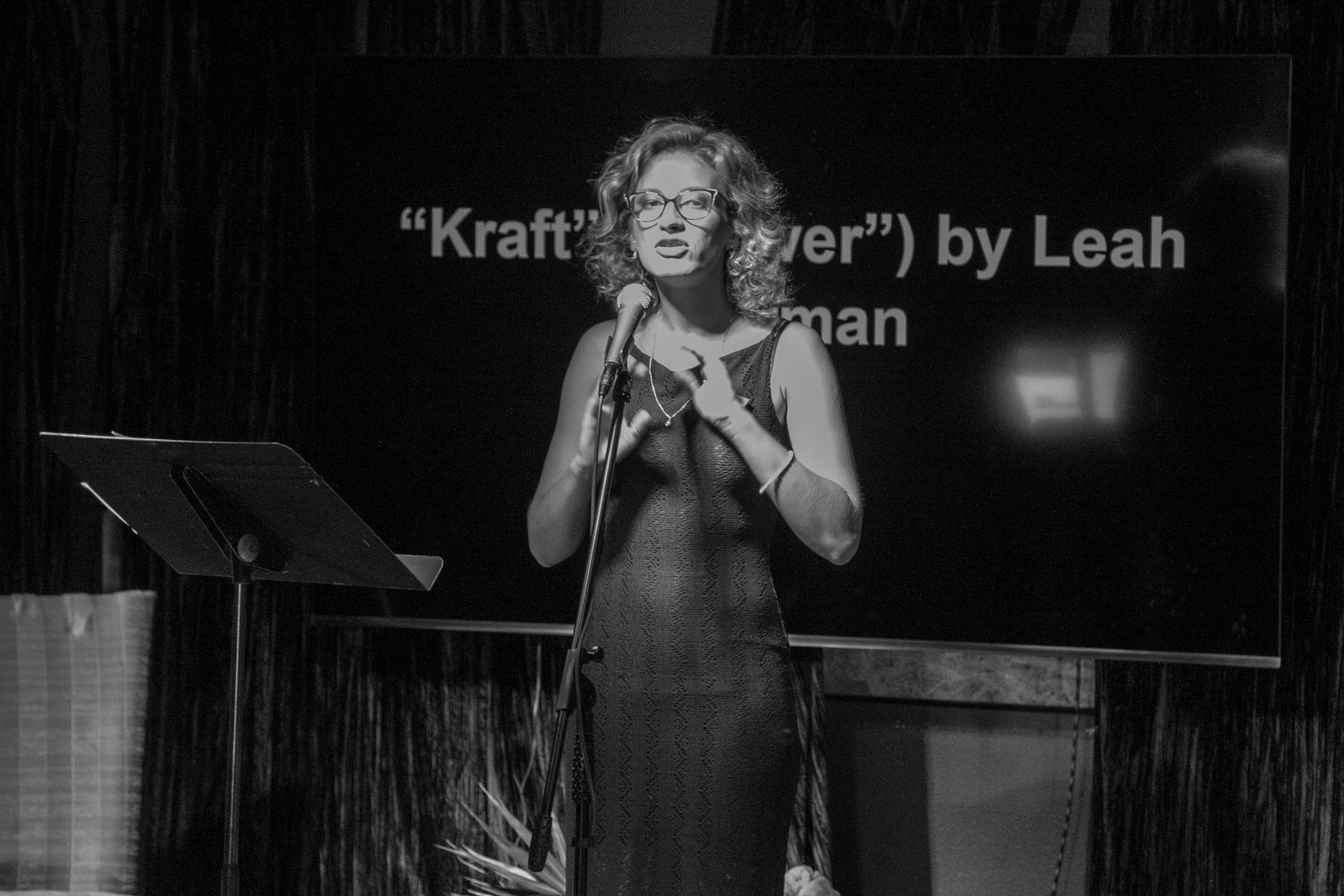 a person in an evening gown and glasses speaking at a microphone