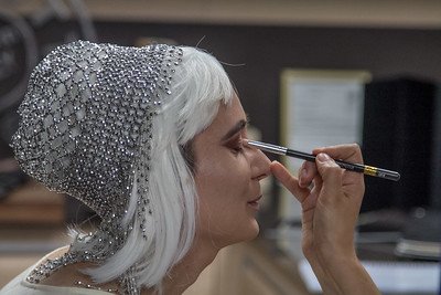 an actress with white hair and metallic head-dress getting make-up