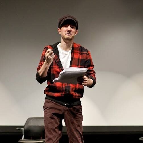 A young person wearing a cap and grimacing