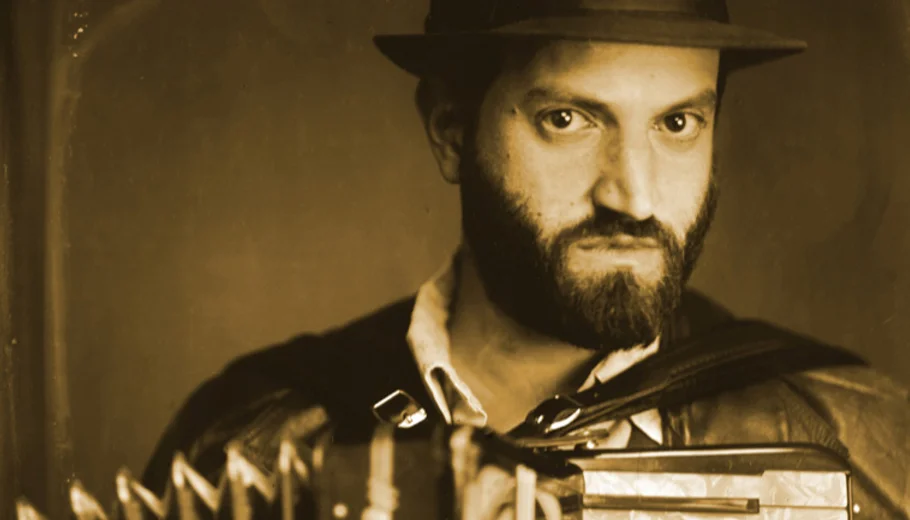 A sepia photograph of Daniel Kahn, with hat and accordion