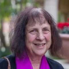 a photo of Karen Bohrer, smiling, a porch with flowers in background