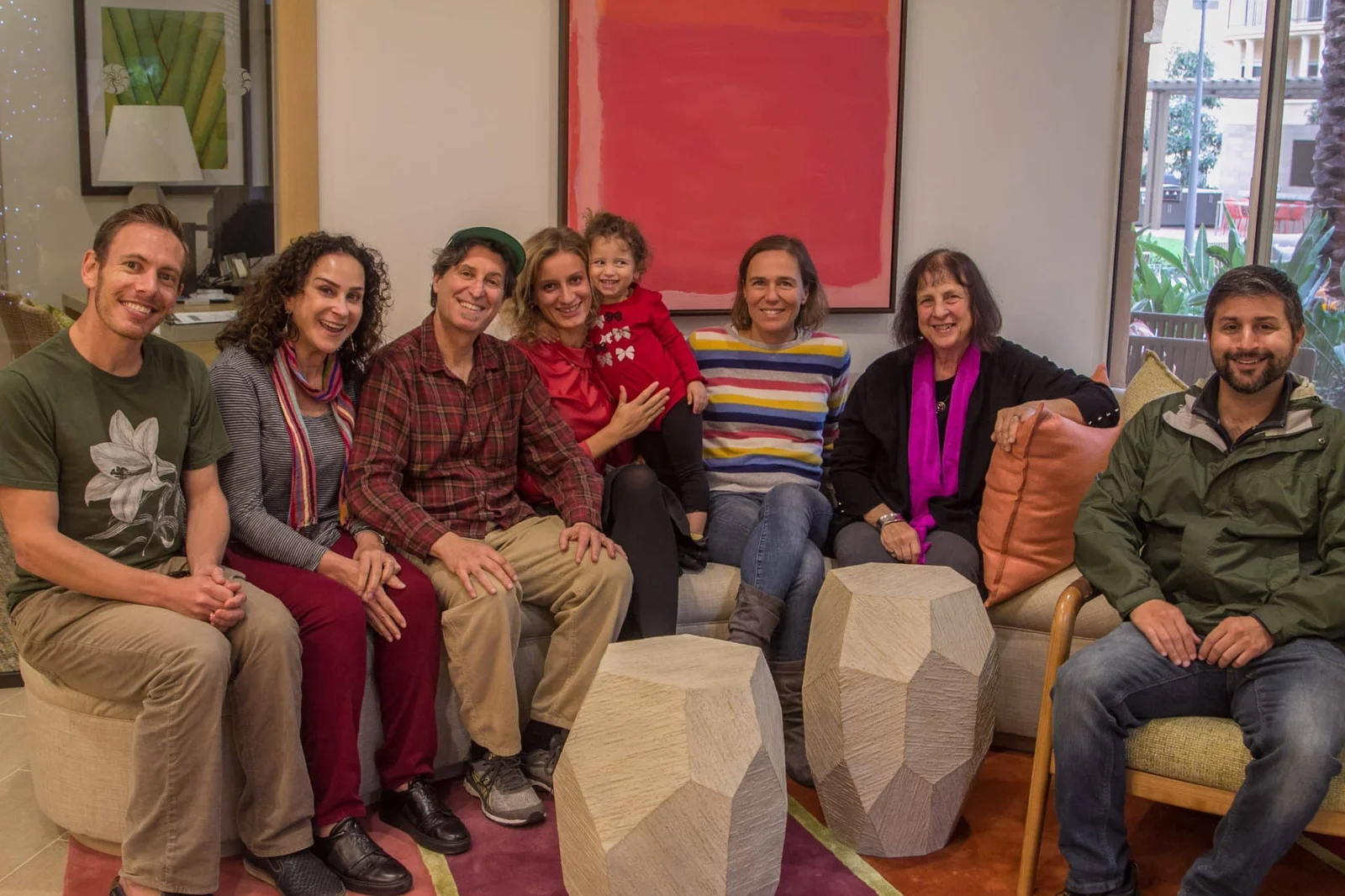 a group of people sitting and smiling, with paintings in the background