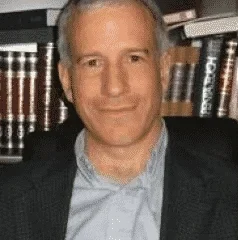 a photo of Rabbi Philip Graubart, smiling, with bookshelves in background