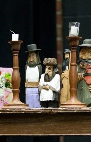 a collection of wooden statuettes, as well as two candlesticks, all on a wooden table